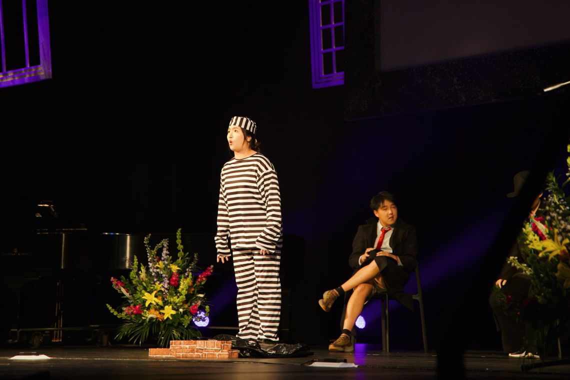 student performing in prison black and white striped outfit