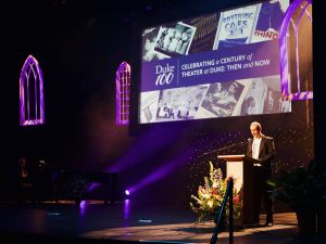 concert stage with screen that reads "celebrating a century of theater at Duke: Then and Now"