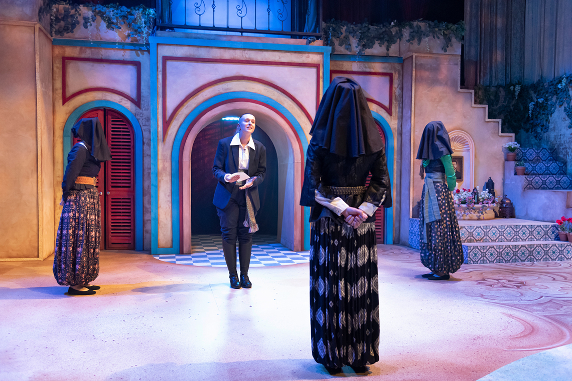 Stage with actor addressing 3 veiled women