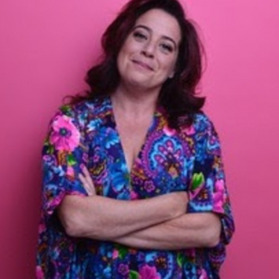 Woman in a flowered dress in front of a pink wall